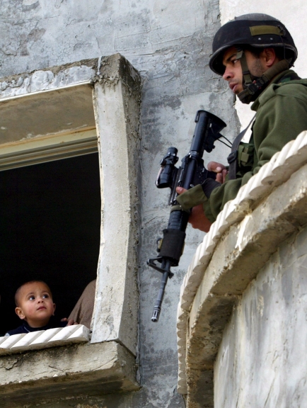 NAB04a NAPLUSA (CISJORDANIA) 20/03/06 : Un ni?o palestinos mira a un soldado israel? apostado en su casa durante una operaci?n militar en el pueblo de Beta junto a la ciudad cisjordana de Naplusa, hoy lunes 20 de marzo. Soldados israel?es registraron el pueblo a primera hora de hoy buscando militantes. EFE/Alaa Badarneh