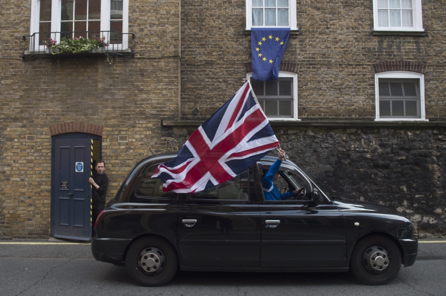 REINO UNIDO UE:HM046 LONDRES (REINO UNIDO) 24/06/2016.- Un taxista londinense ondea una bandera británica mientras circula por una calle donde una bandera europea ondea en una ventana en Londres (Reino Unido) hoy, 24 de junio de 2016. El Reino Unido votó a favor de abandonar la Unión Europea (UE) tras conseguir el 52% del respaldo ciudadano frente al 48% que apoyó la permanencia, en el referéndum celebrado este jueves sobre su relación con el bloque comunitario. EFE/Hannah Mckay